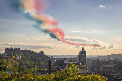 Red arrows flypast over edinburgh city in scotland at sunset.
