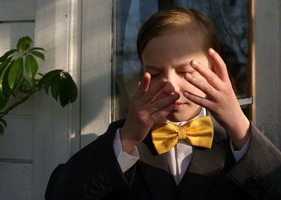 Close-up of boy rubbing eyes while standing outdoors