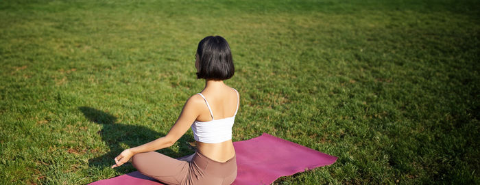 Rear view of woman sitting on grassy field