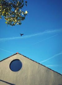 Low angle view of airplane flying against blue sky