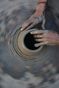 Hands working on pottery wheel and making a pot