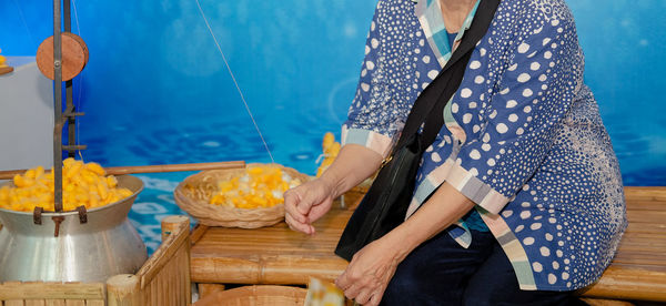 Midsection of woman making silk cloth from cocoons