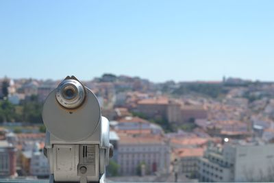 Close-up of coin-operated binoculars against cityscape