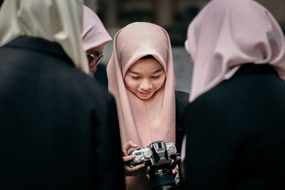 Teenage girl with women wearing hijab holding camera