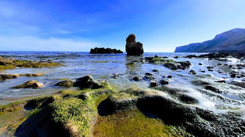 Scenic view of rocks on beach against sky