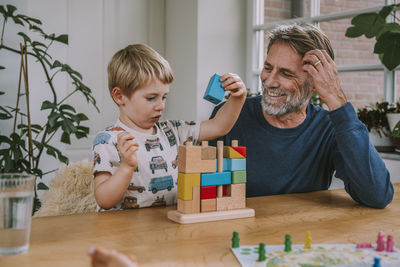 Father watching son playing with puzzle while sitting at home