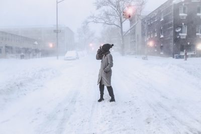 Side view of woman standing on snowcapped street during winter