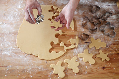 Cropped hands of chef cutting dough with pastry cutter at table