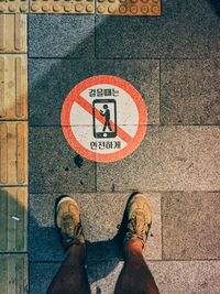 Low section of person standing on road sign