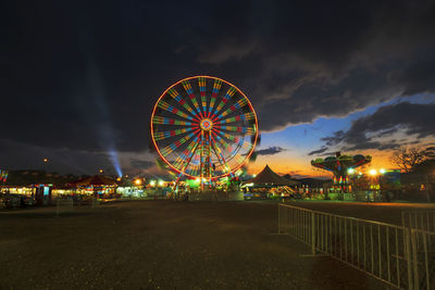 Illuminated ferris wheel against sky at night