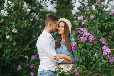 Loving happy young couple embraces in the park of blooming lilac in spring person
