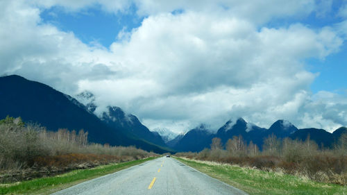 Road by mountains against sky