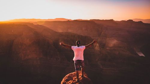 Rear view of man standing on landscape against sky