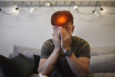 Ill man on sofa with face in hands