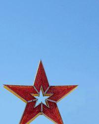 Low angle view of red star against clear blue sky