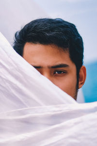 Close-up portrait of handsome young man face covered with sheet