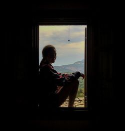 Side view of woman looking through window