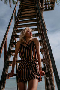 Portrait of young woman standing against sky