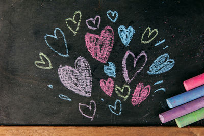 Drawing heart-shape with colored chalk on blackboard