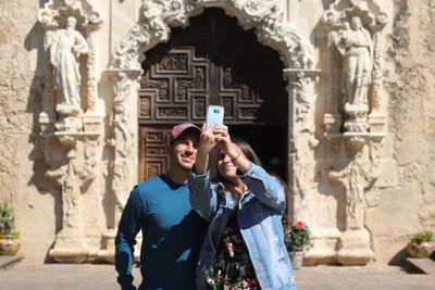 Young couple kissing against building