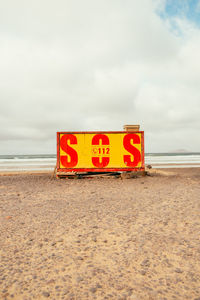 Information sign on beach against sky