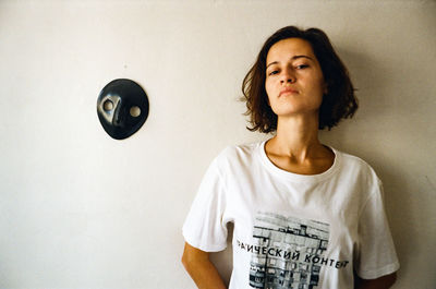 Portrait of young woman standing against wall