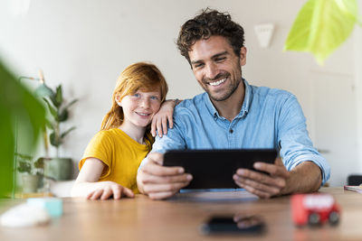 Portrait of smiling young man using phone on table