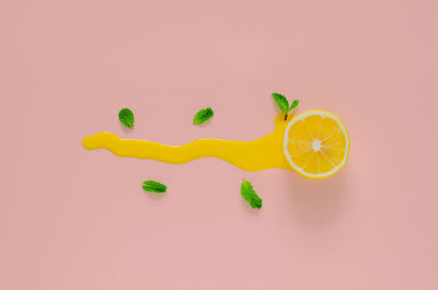Slice lemon with mint leaves and poster color that drop on pink background. minimal summer concept.