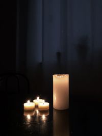 Close-up of lit candles on table in darkroom