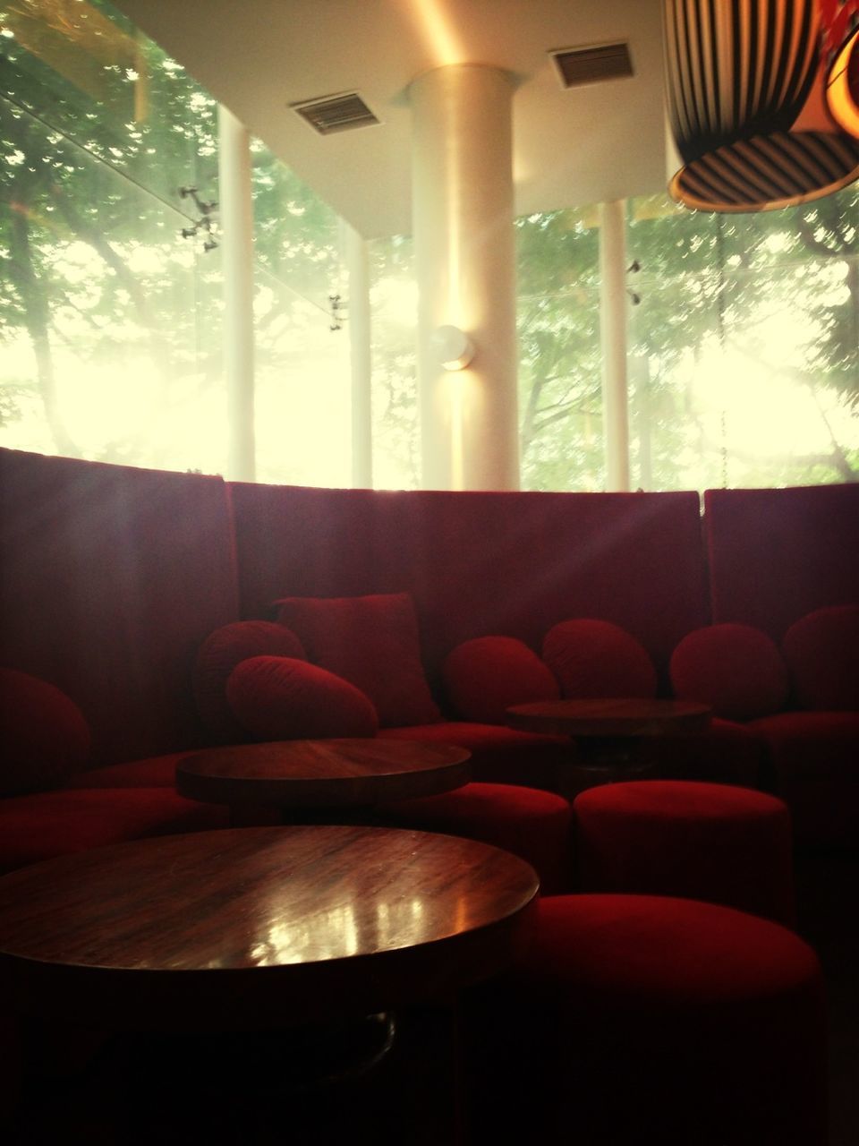 indoors, window, glass - material, chair, transparent, home interior, sunlight, curtain, absence, table, tree, empty, no people, lighting equipment, hanging, seat, day, house, restaurant, sunbeam
