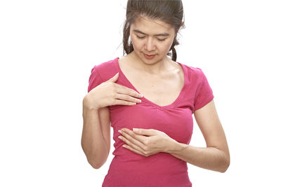 Woman with hands on chest standing against white background