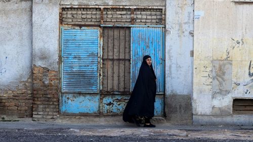 Side view of woman standing against old building