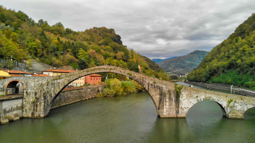 Arch bridge over river against sky