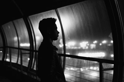 Side view of woman standing in illuminated building