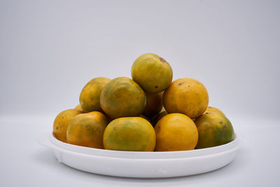 Close-up of fruits in bowl over white background