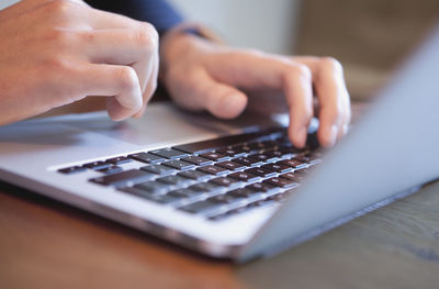 Close-up of man using laptop on table