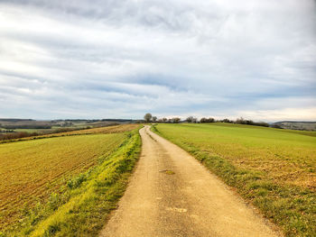 Open road in the countryside, rural landscape, cloudy sky, fields, horizon over land , sunlight 