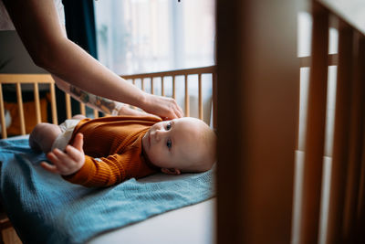 Mother changing dress of baby boy at home