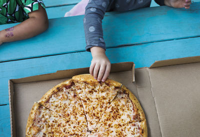 Overhead view of girl holding pizza slice on table