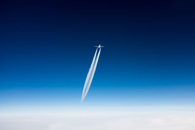 Airplane and vapor trail against sky