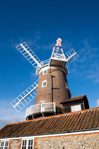 Low angle view of traditional windmill against blue sky