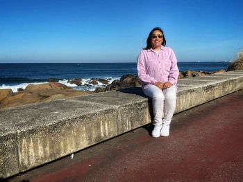 Portrait of young woman standing against sea