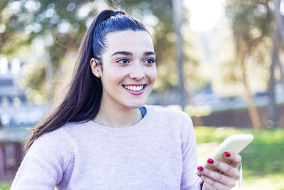 Portrait of smiling young woman holding smart phone
