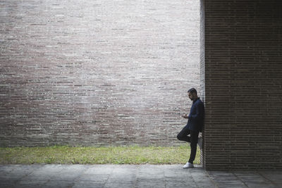 Side view of contemplating man standing by wall