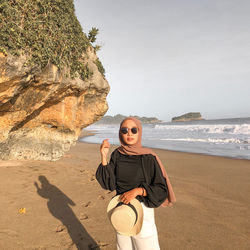 Full length of man on rock at beach against sky