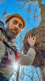 Low angle portrait of man against bare tree