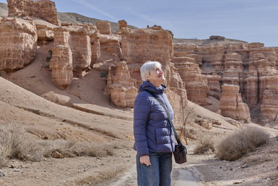 Senior white woman looking up over background of rocks of charyn canyon, kazakhstan.
