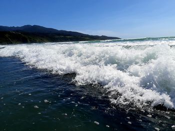 Water splashing in sea against clear blue sky