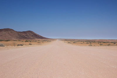 Scenic view of desert road against clear sky