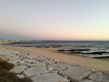 Scenic view of beach against clear sky during sunset